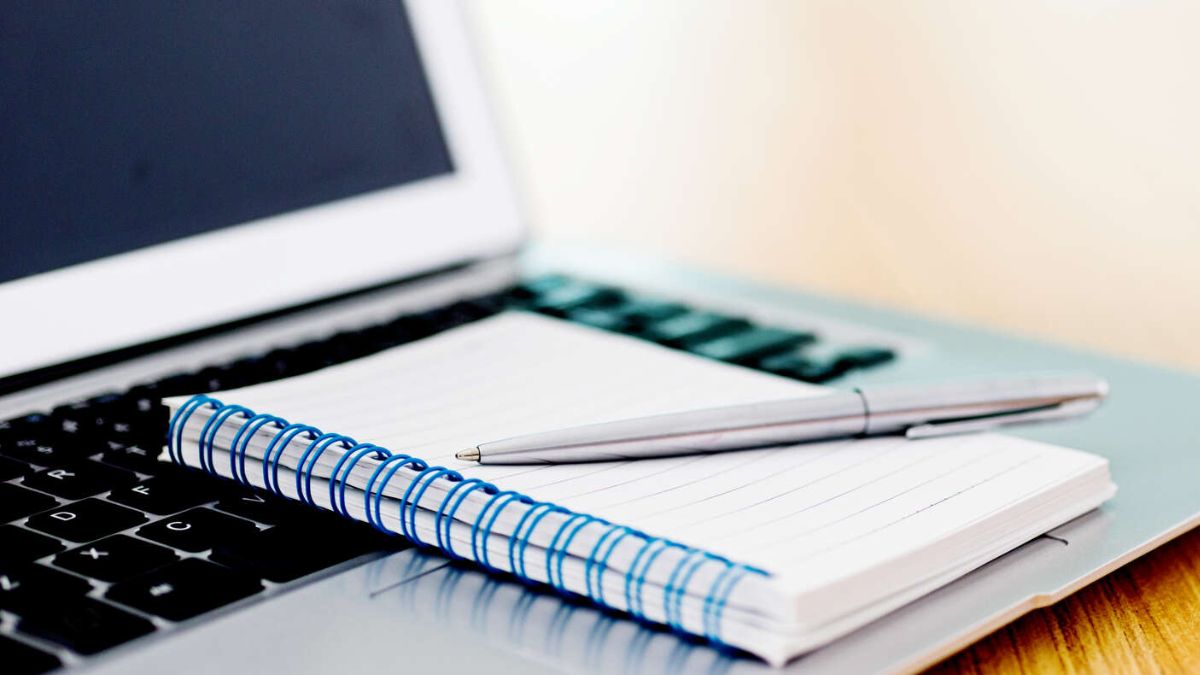 Laptop with pen and spiral notebook on desk