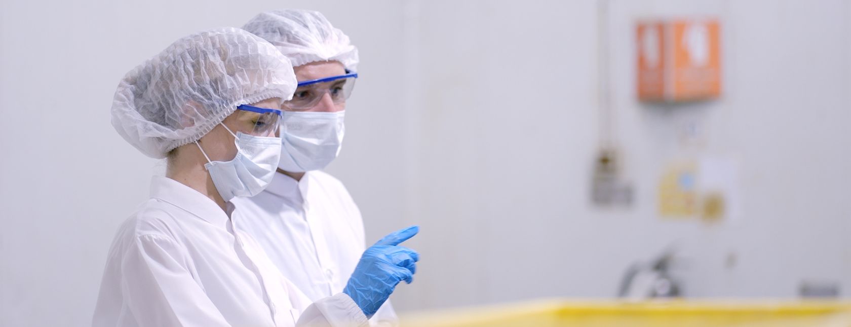 Produktionsmedarbejdere i hvide sterile uniformer forhindrer kontaminering